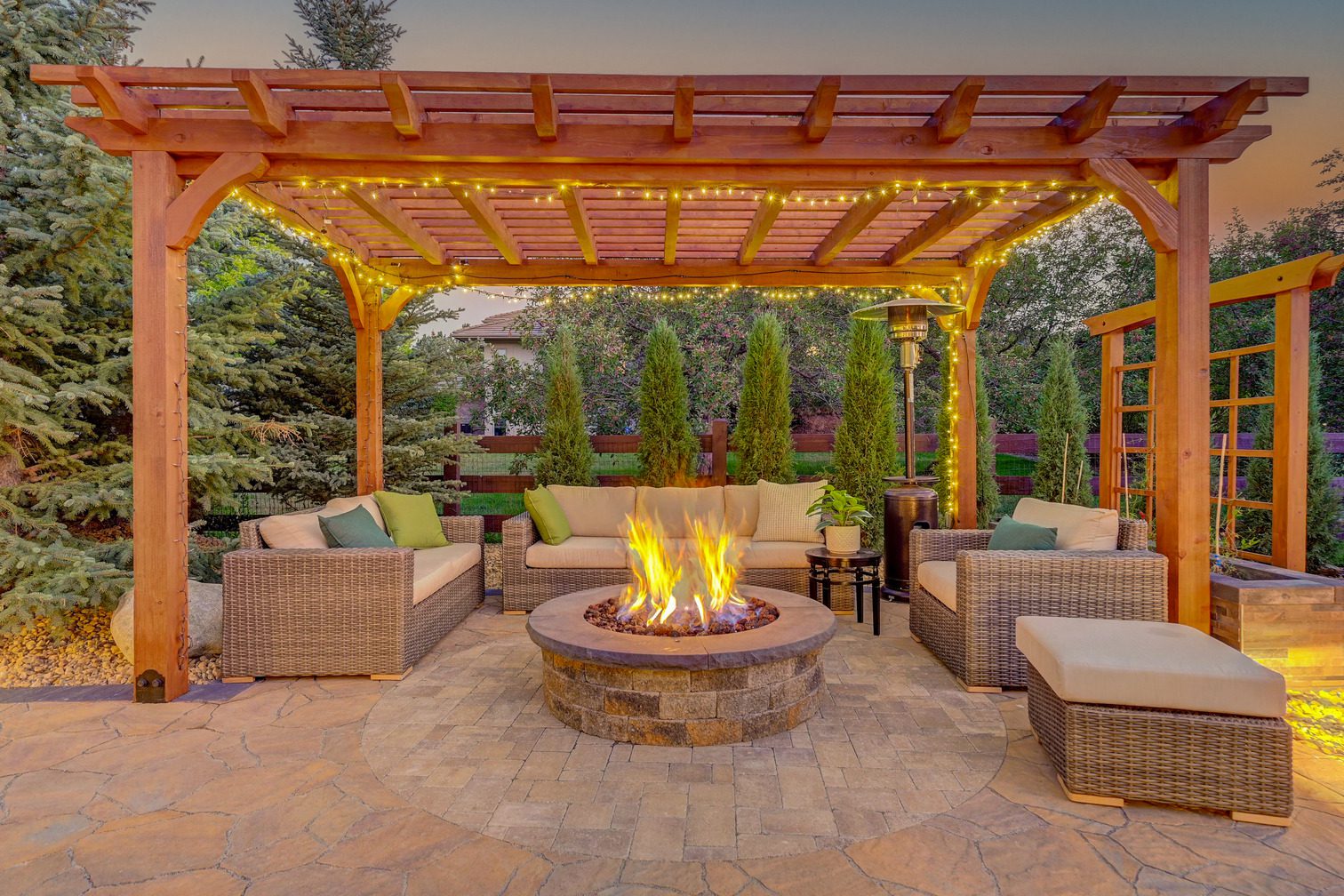 Custom patio with pergola, fire pit, and stone hardscaping at twilight in Boulder County Colorado