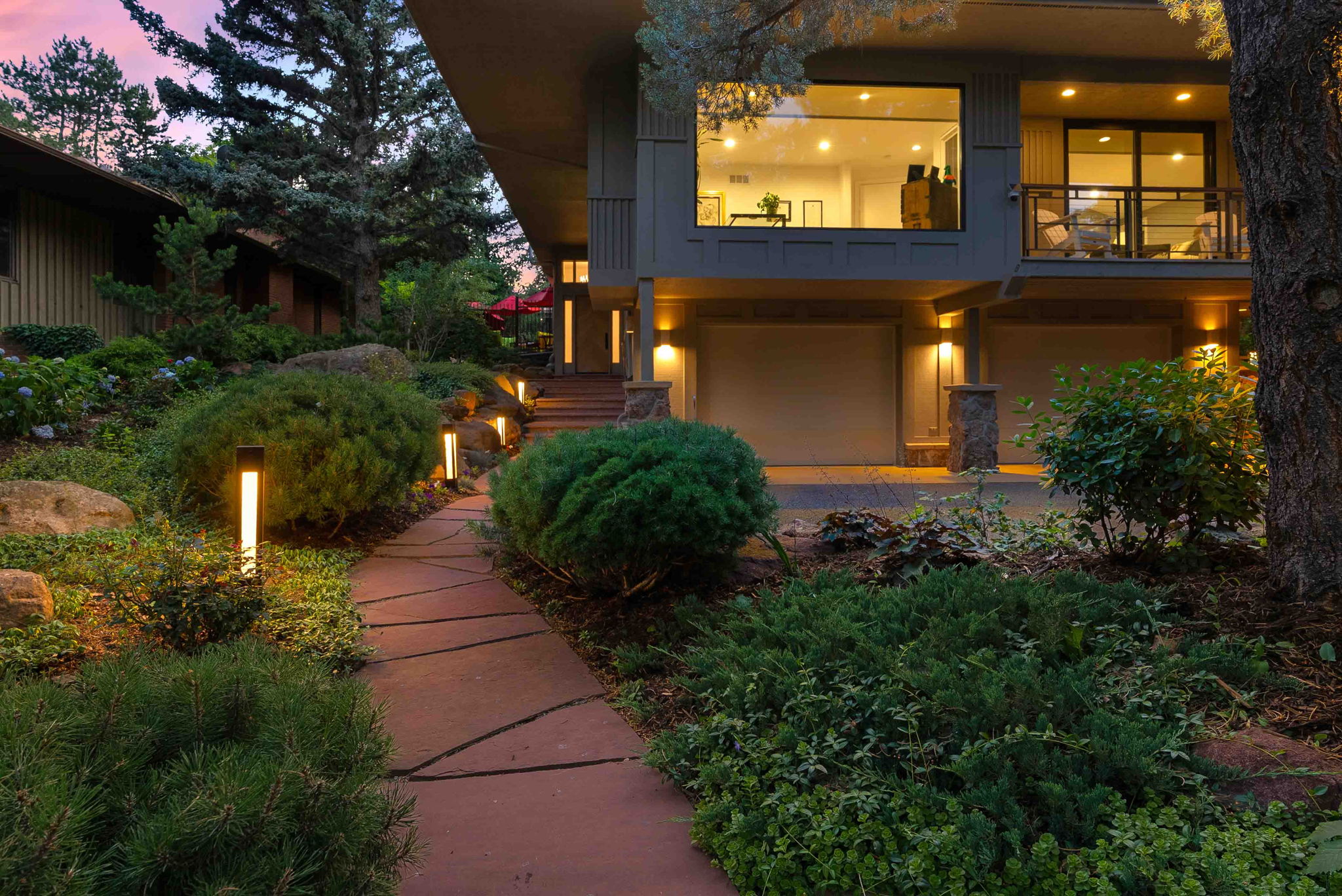 Professionally maintained landscape with manicured shrubs, pathway lighting, and lush garden beds at a Boulder Colorado home at twilight