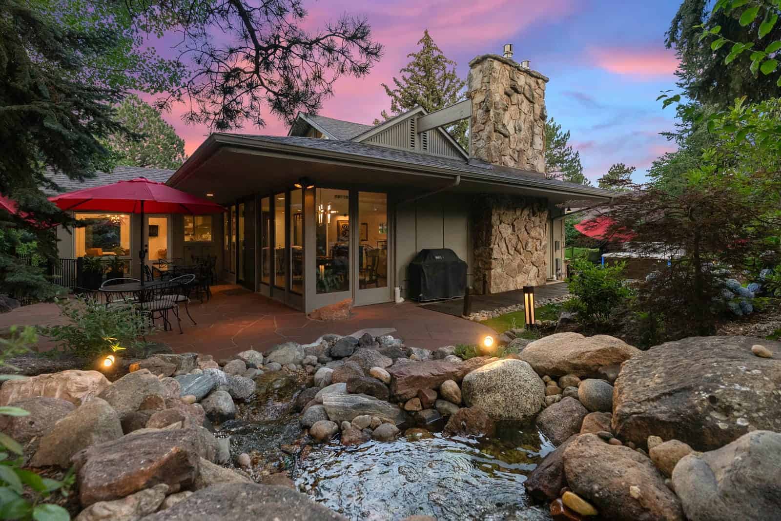 Custom backyard patio and outdoor living space at dusk in Boulder, CO by Nature's Way Landscapes
