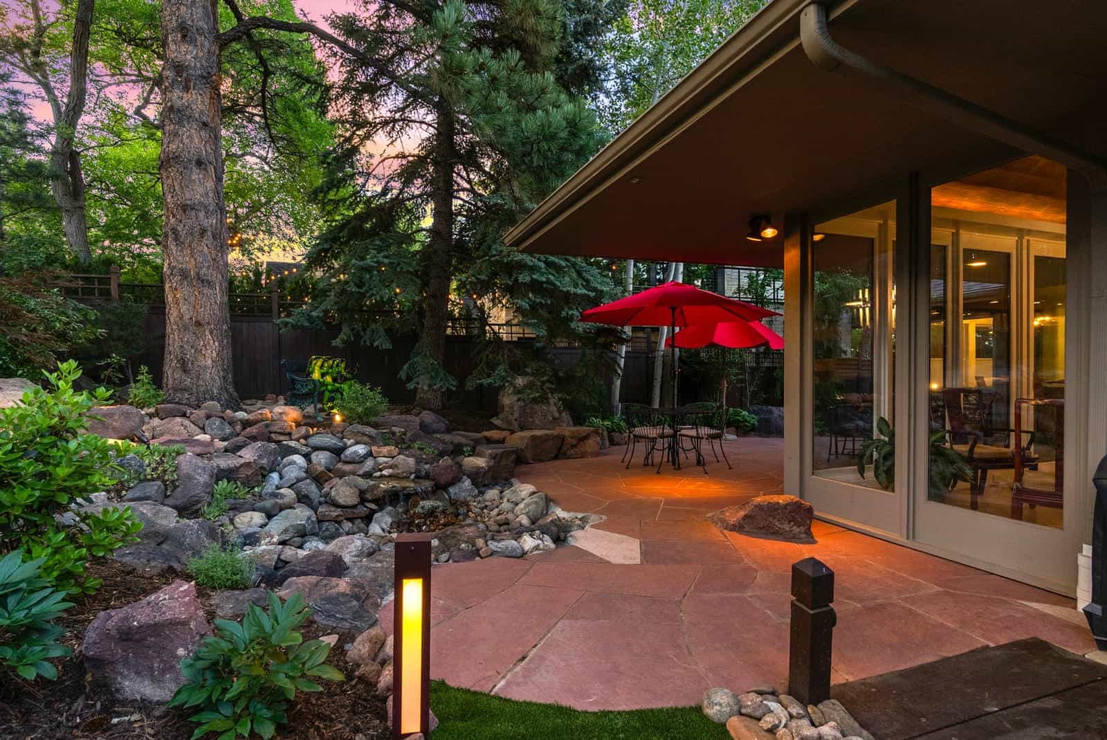 Backyard landscape design with outdoor dining at dusk in Boulder, CO by Nature's Way Landscapes
