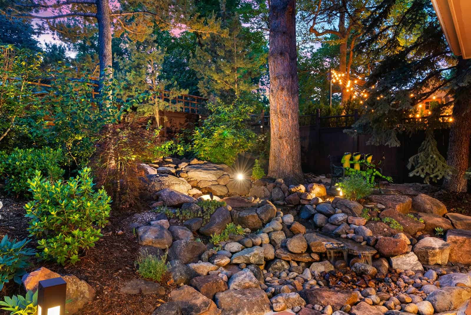 Water feature with uplighting and bollard lights at night in Boulder, CO by Nature's Way Landscapes