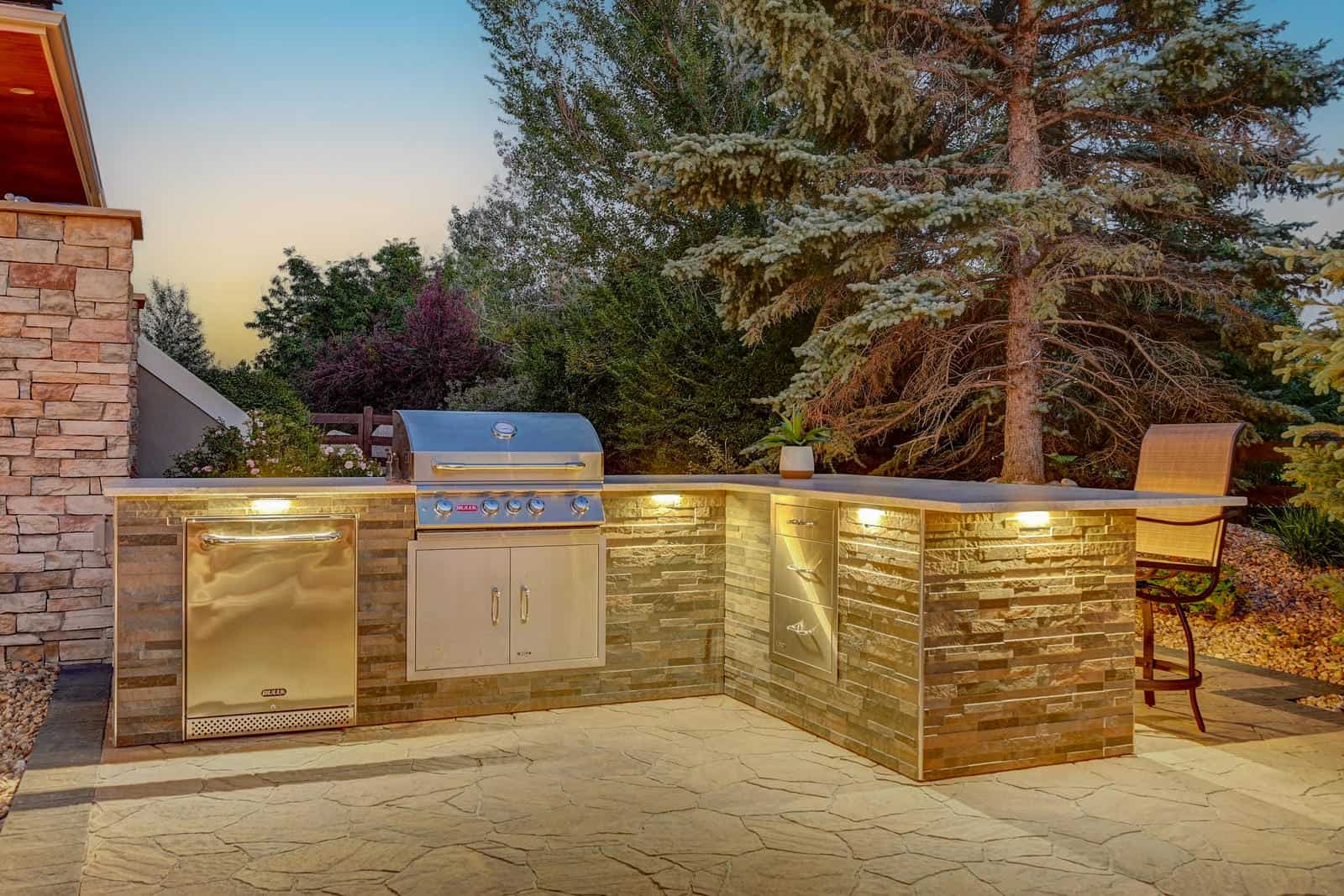 Outdoor kitchen and seating area at dusk in Boulder, CO by Nature's Way Landscapes