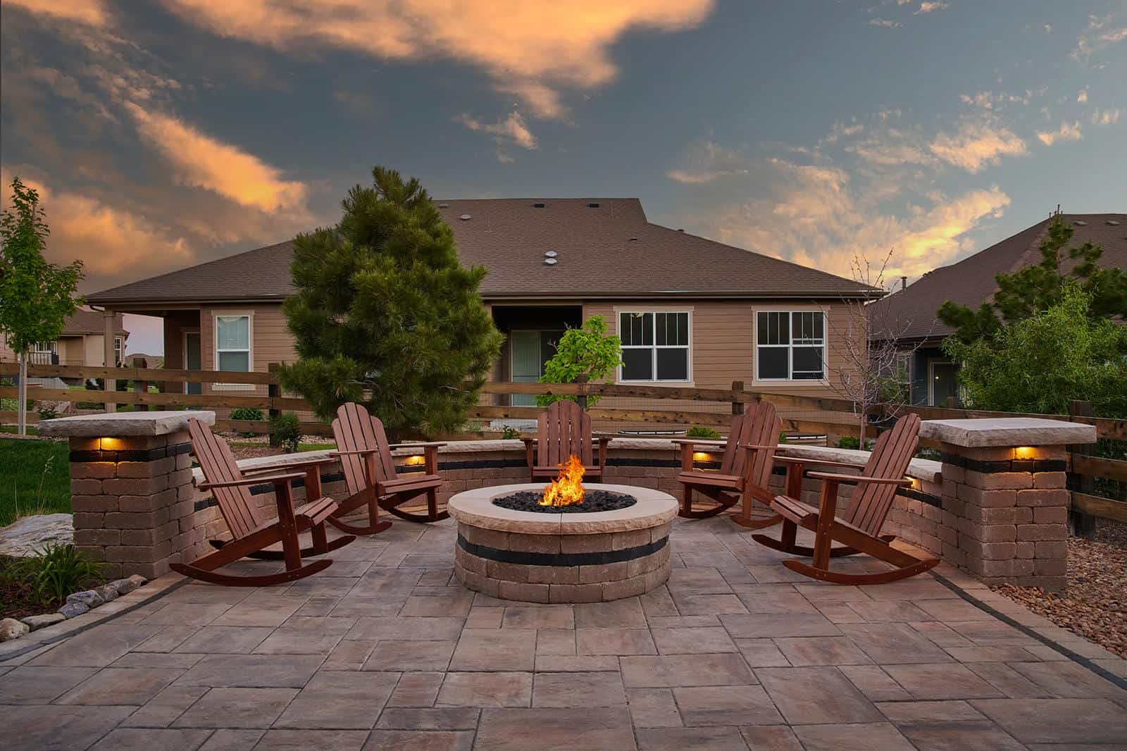 Fire pit seating area with Adirondack chairs at dusk in Broomfield, CO by Nature's Way Landscapes