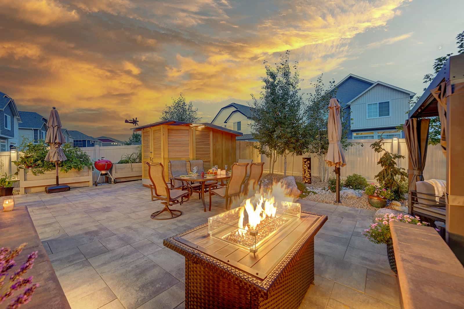 Custom patio and fire table installation at dusk in Broomfield, CO by Nature's Way Landscapes