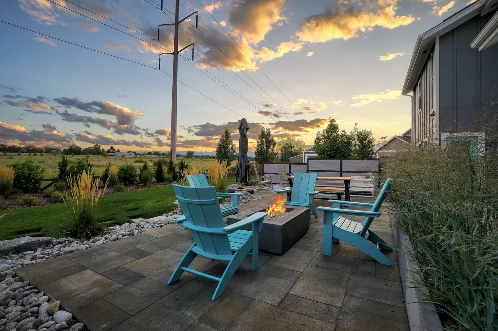 Fire pit patio with Adirondack seating at sunset in Erie, CO by Nature's Way Landscapes