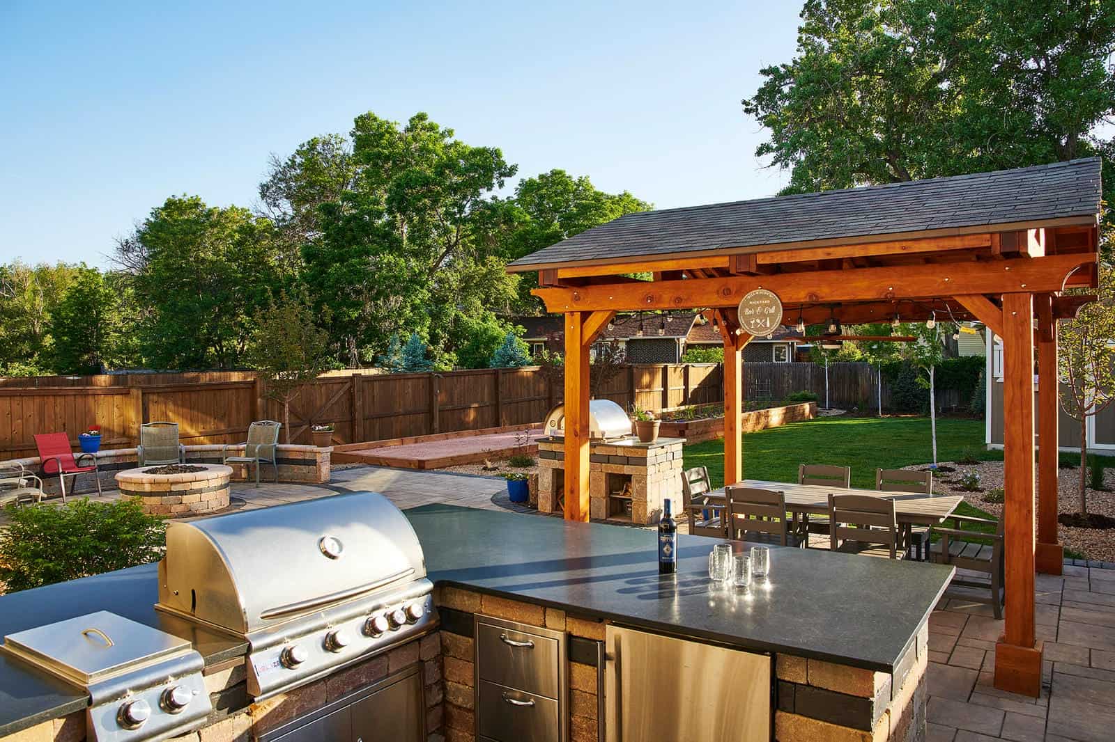 Pergola and outdoor grill station at dusk in Lafayette, CO by Nature's Way Landscapes
