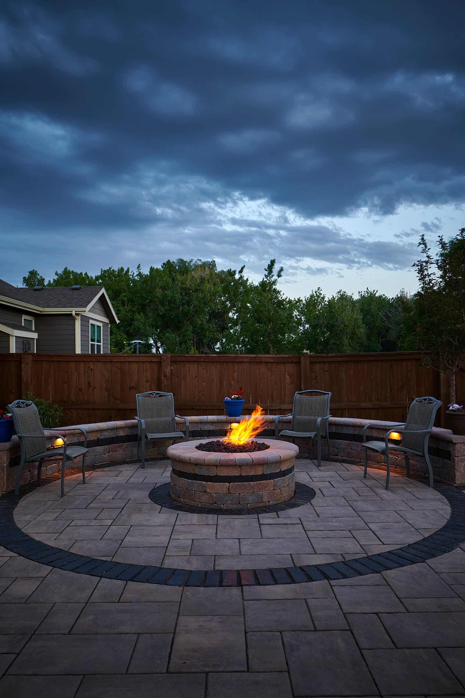Fire pit patio installation at night in Lafayette, CO by Nature's Way Landscapes