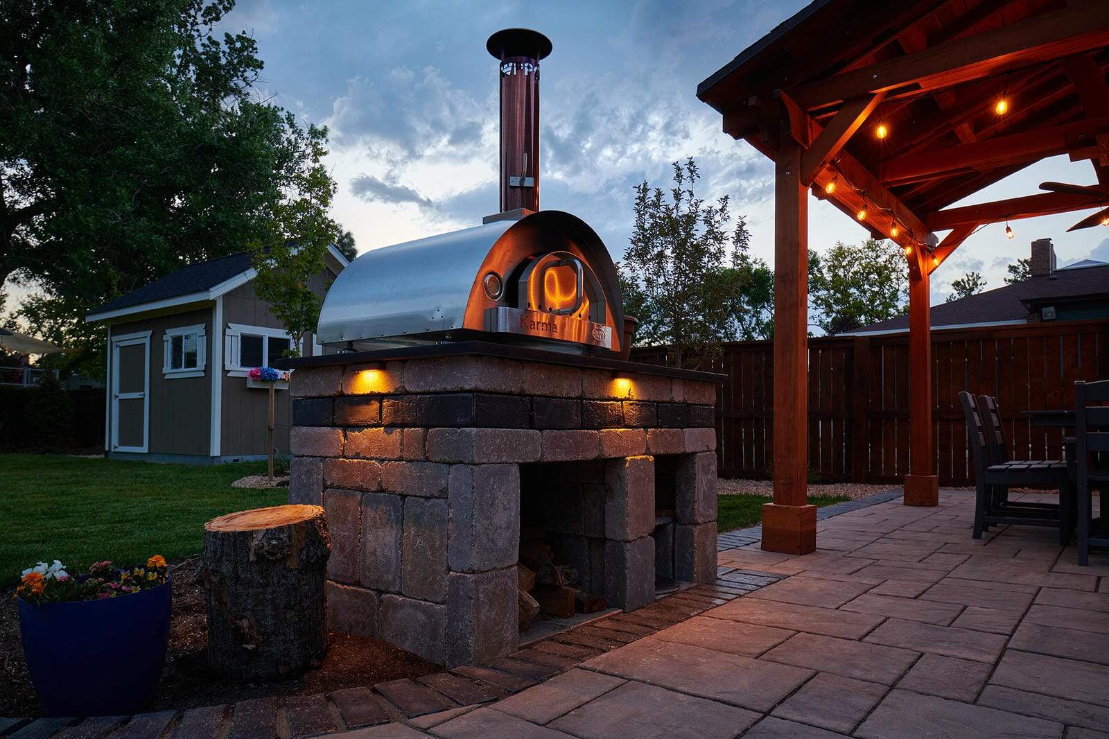 Pergola and outdoor grill station at dusk in Lafayette, CO by Nature's Way Landscapes