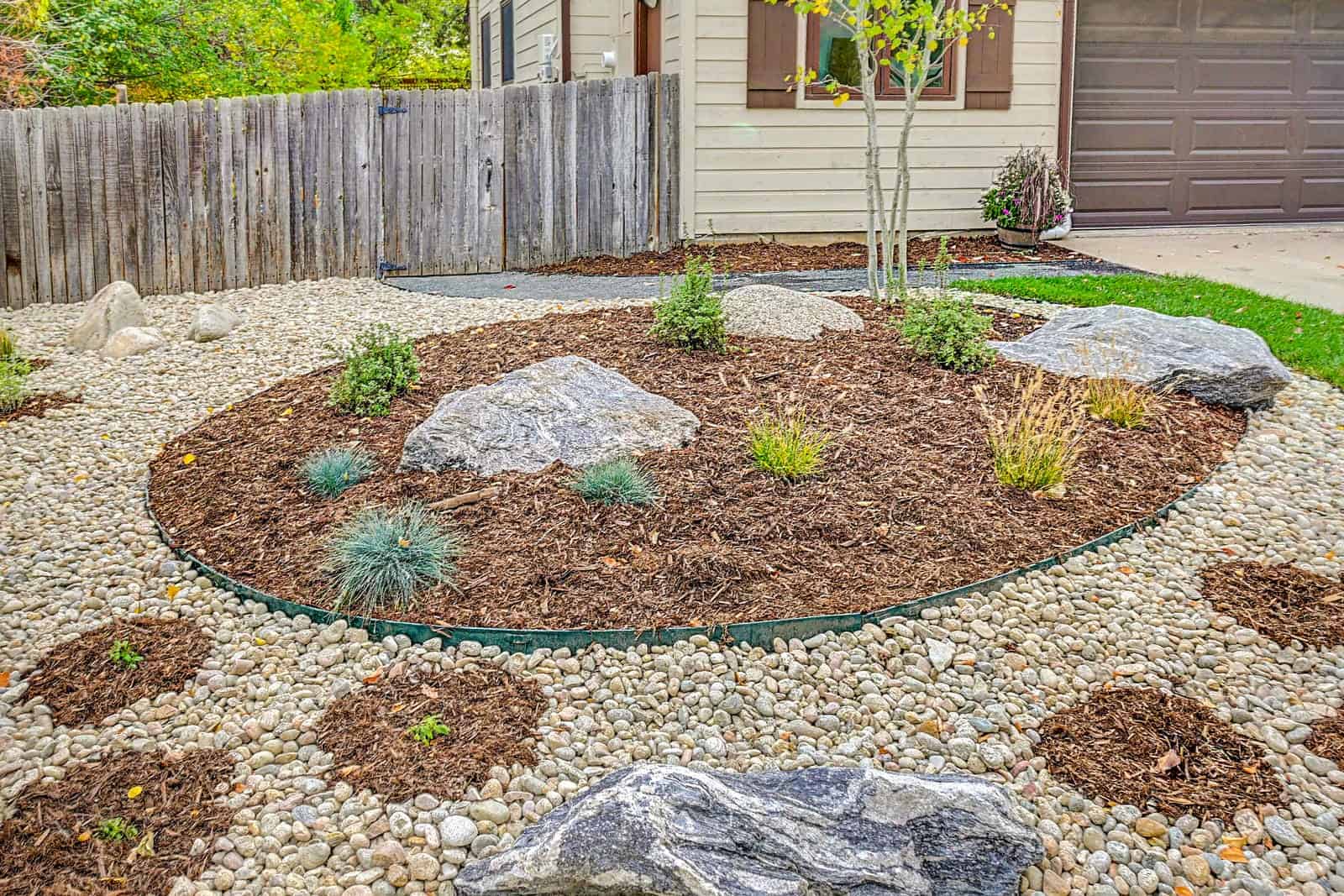 Xeric planting bed with boulder accents and drought-tolerant plants in Louisville, CO by Nature's Way Landscapes